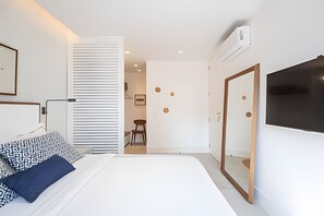 Quarto de hotel moderno com uma cama grande, uma escrivaninha e uma TV fixada na parede.