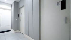 Un corridoio con una porta, una griglia di ventilazione e un interruttore della luce sul muro.