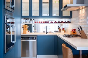 A modern kitchen with built-in appliances, a central island, and a window overlooking the city. - Rua Dias Ferreira, 646 - Tesouro Escondido no Leblon (Rio de Janeiro)
