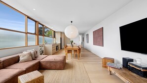 En moderne stue med en stor sofa, spisebord og fjernsyn.