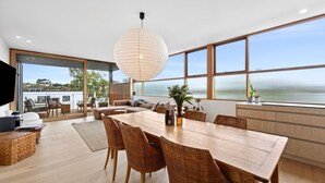 Et moderne køkken med et stort træbord, fletstole og en hængende lampe.