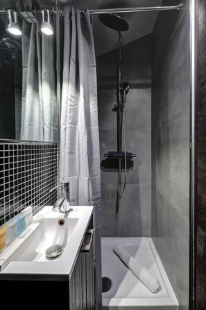 Ett modernt badrum med en dusch som är avskärmad med glasväggar, ett vitt handfat och en handdukshängare.