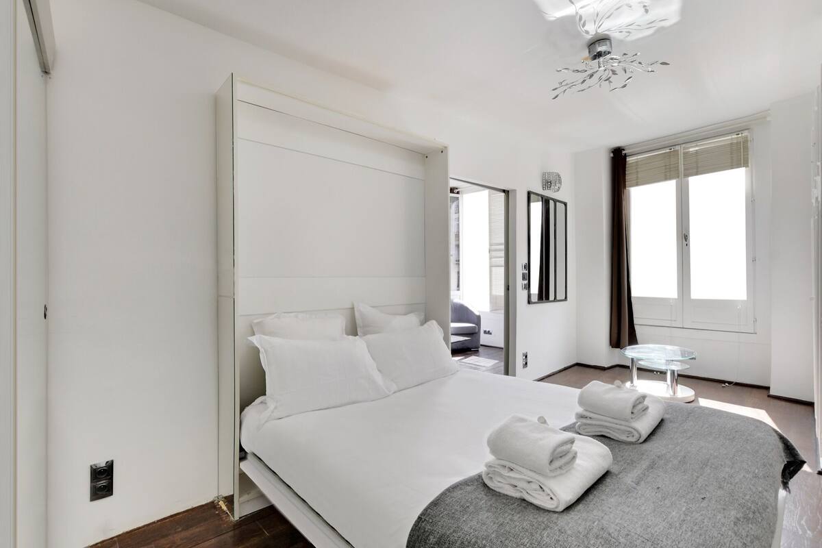 Une chambre d’hôtel moderne avec un grand lit, une petite table ronde et une vue sur l’extérieur.
