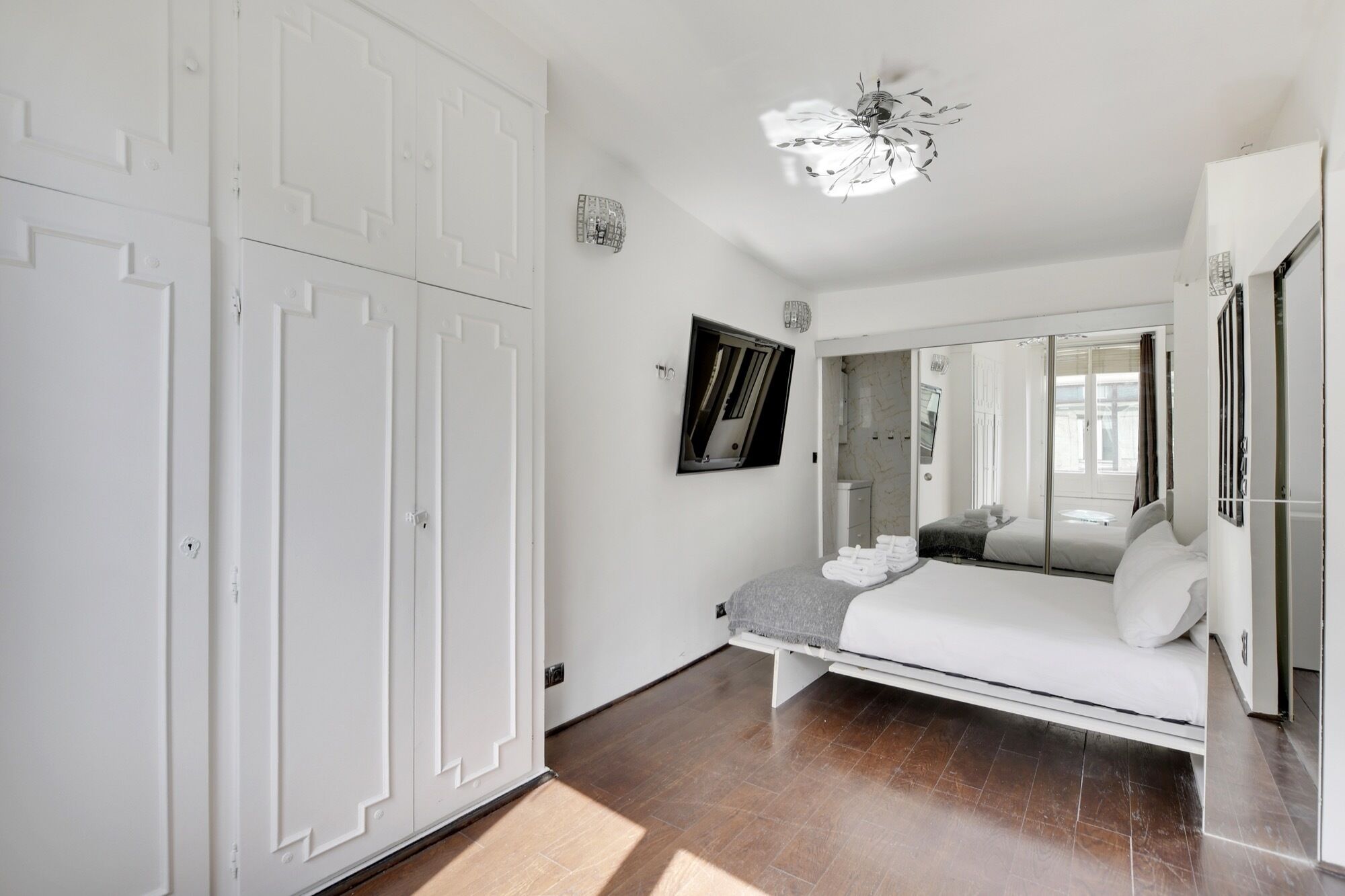 A bedroom with a bed, a wardrobe, a mirror, and a ceiling fan.