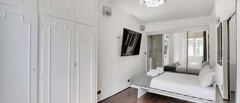 A bedroom with a bed, a wardrobe, a mirror, and a ceiling fan.