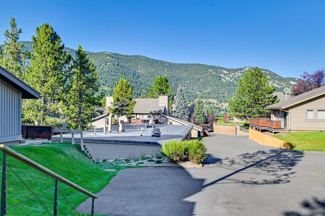 A residential area with houses, a driveway, and a mountain backdrop.