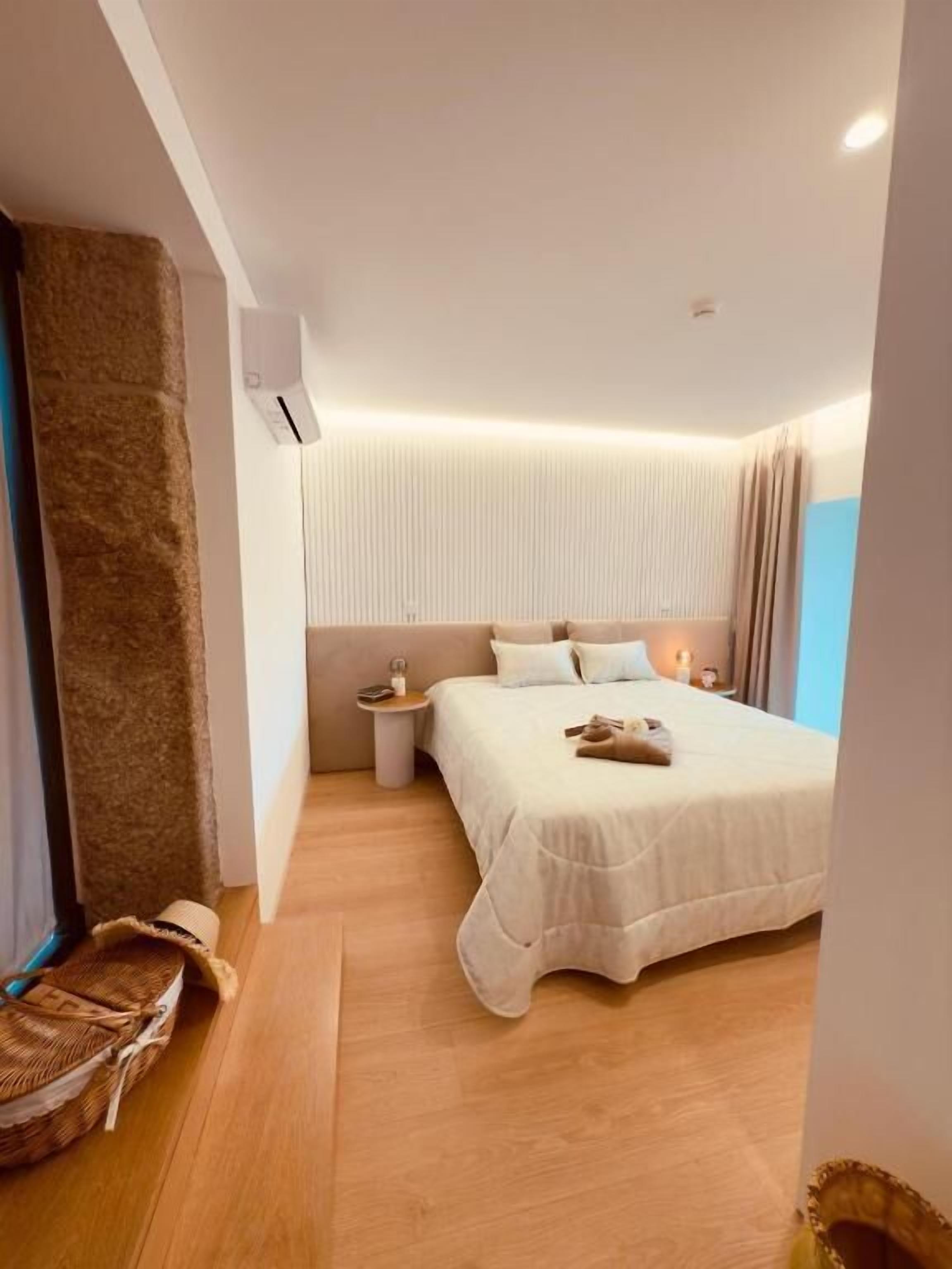 Quarto moderno com uma cama grande, mesa de cabeceira e ar condicionado na parede.