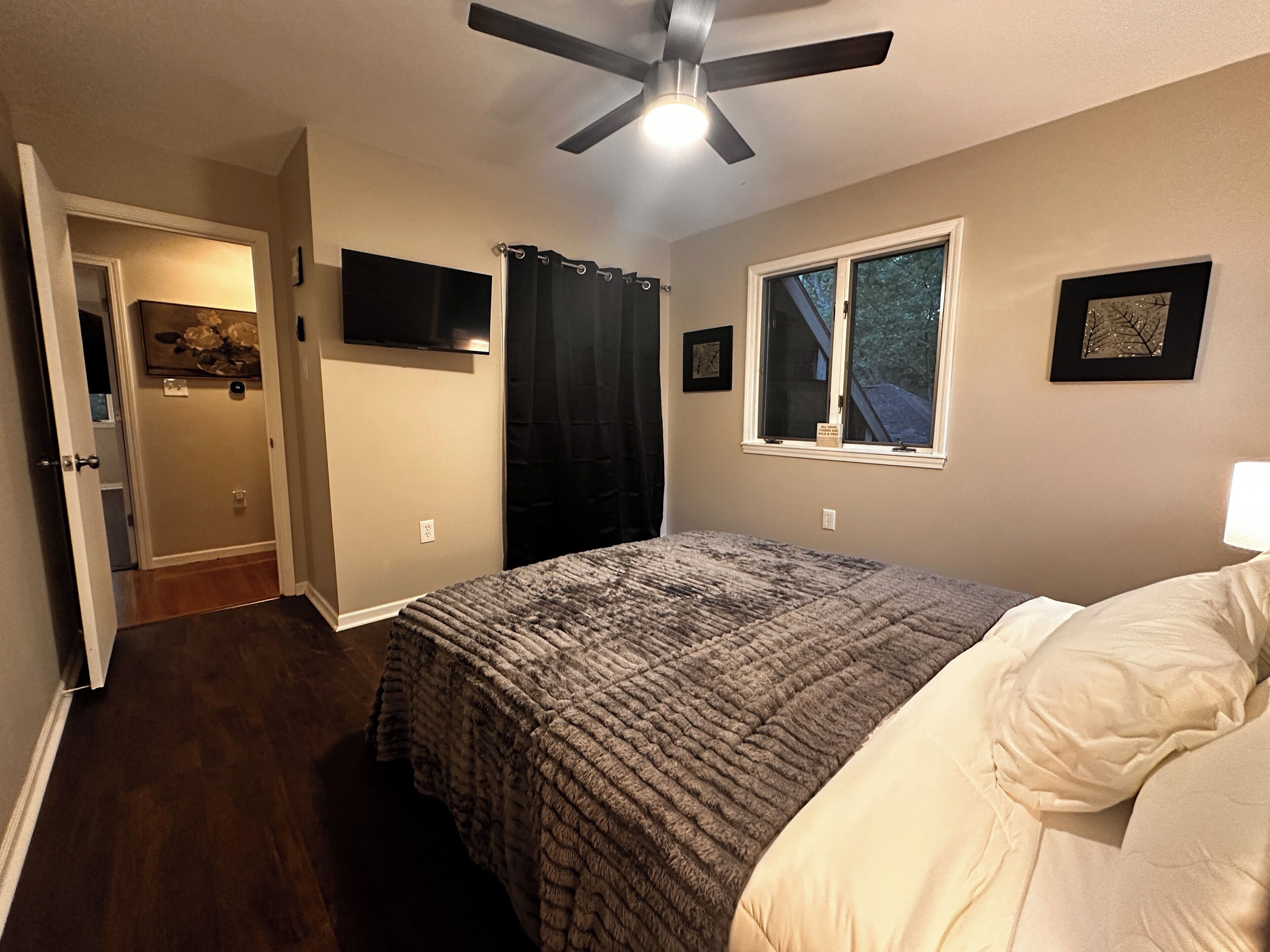 Ein Schlafzimmer mit Bett, Deckenventilator, Fenster und Tür.