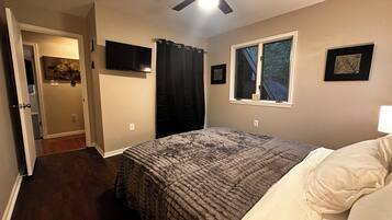 Ein Schlafzimmer mit Bett, Deckenventilator, Fenster und Tür.