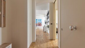 A hallway with wooden flooring, a white door, and a view into a room with a painting and shelves. - Vetro Apartment by Wonderful Italy  (Palermo)