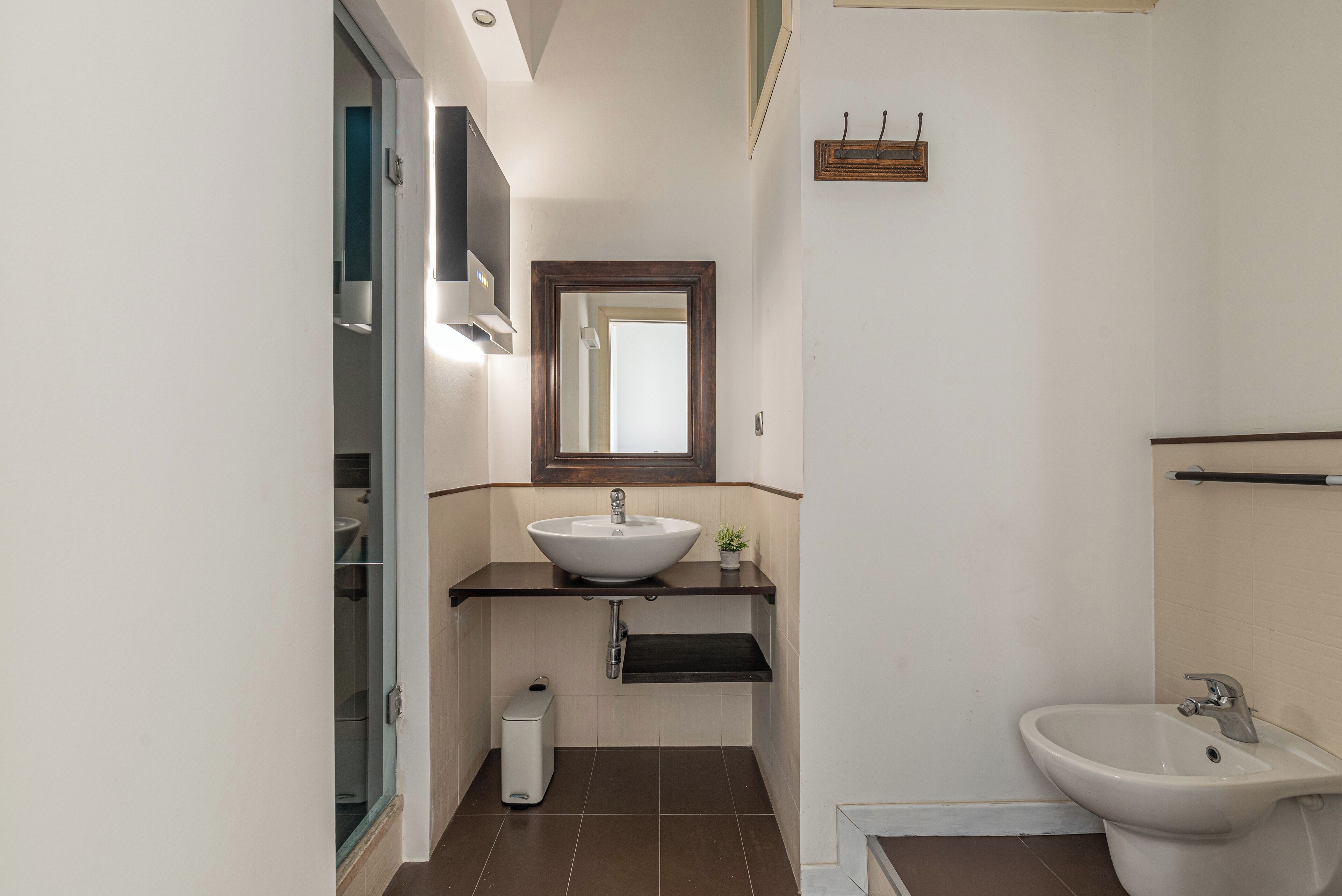 A bathroom with a white sink, a mirror above it, a bidet, and a toilet.