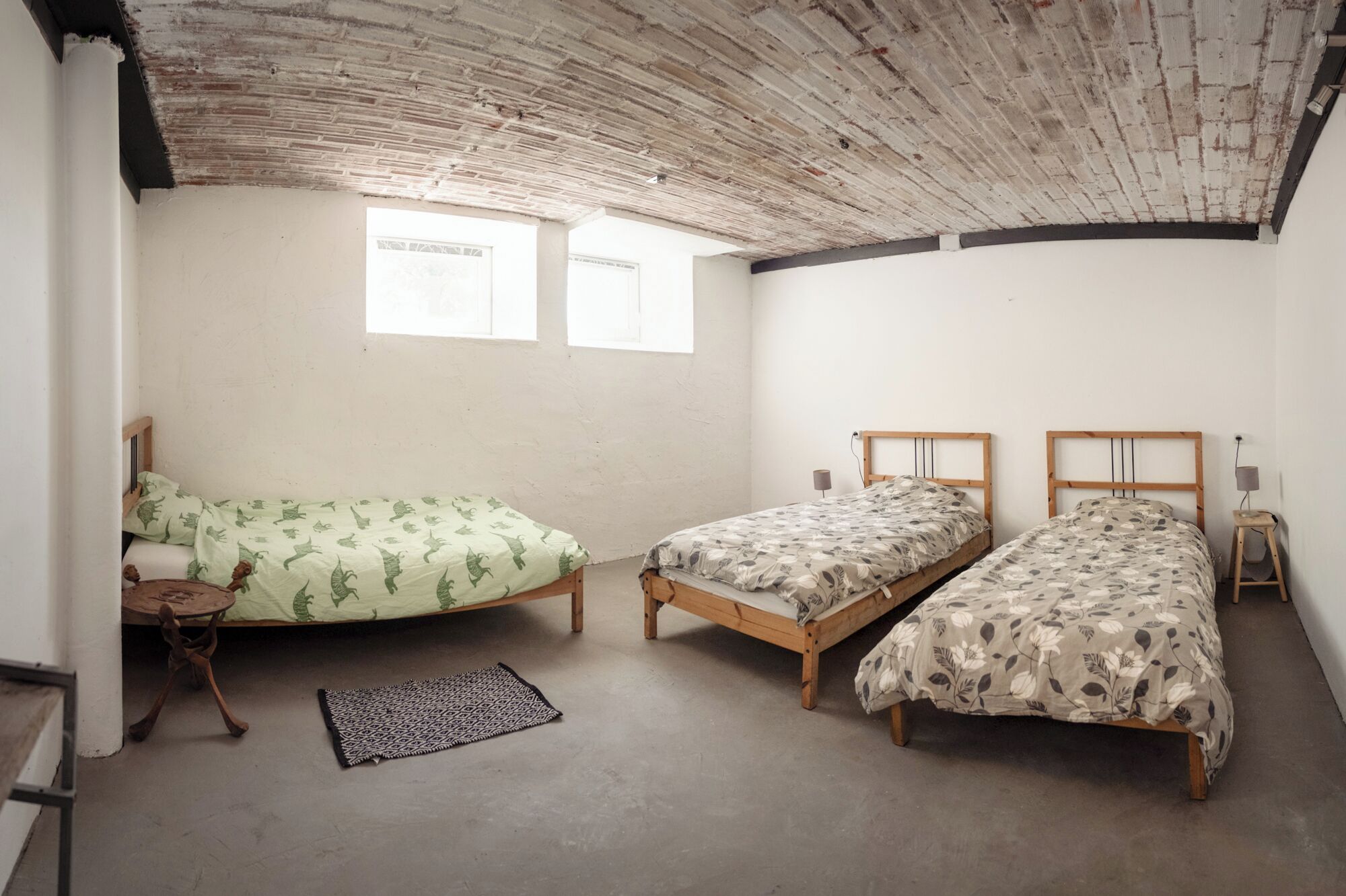 A room with two wooden beds, a small table, and a rug.