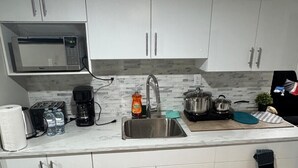 A modern kitchen with white cabinets, a stainless steel sink, a microwave, and a coffee maker.