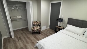 A bedroom with a bed, a chair, a wardrobe, and a bedside table.