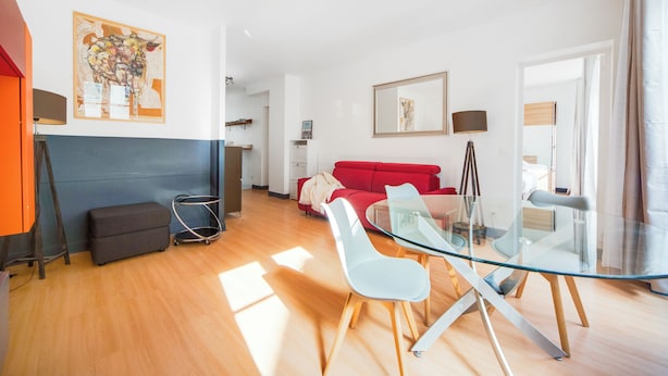 Ein modernes Wohnzimmer mit einem Glastisch, einem roten Sofa und einem Bild an der Wand.