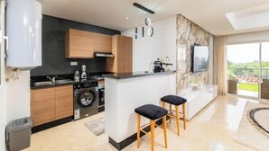 A modern kitchen with a central island, built-in appliances, and a large window offering a view of the outdoors.