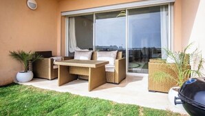 A balcony with wicker furniture, a barbecue grill, and potted plants.