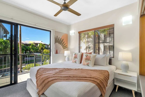 Recharge in the king-sized bedroom, a peaceful retreat featuring split system air conditioning, a ceiling fan, and sliding doors that open onto a leafy private balcony.