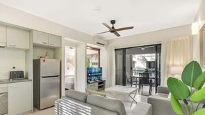 A modern living room with a sofa, a television, and a dining area with a table and chairs.