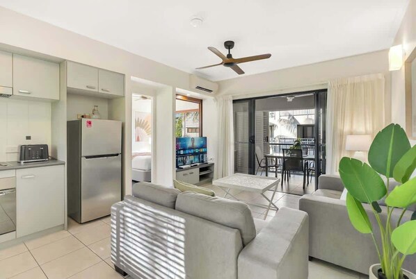 A modern living room with a sofa, a television, and a dining area with a table and chairs.