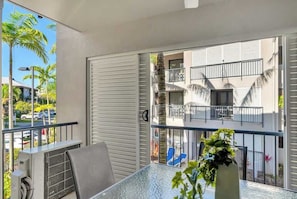 Un balcone con un tavolo in vetro, una sedia e un vaso con una pianta.