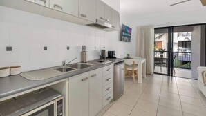 A modern kitchen with stainless steel appliances, a dining area with a table and chairs, and a balcony with a view.