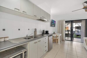 Una cucina moderna con elettrodomestici in acciaio inossidabile, un'area pranzo con tavolo e sedie, e un balcone con vista.