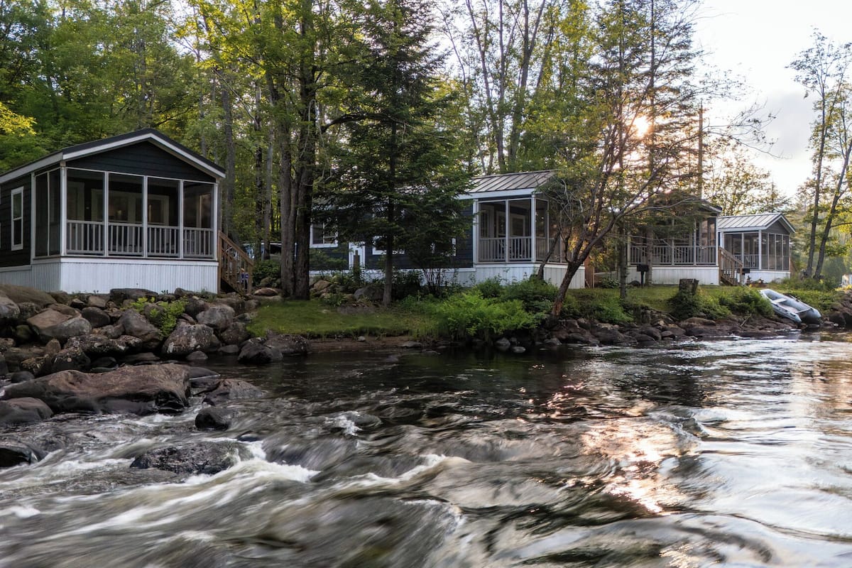 A river flowing through a wooded area with cabins.