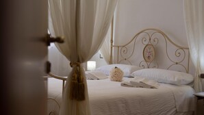 A bed with white bedding, a decorative headboard, and a bedside table with a lamp. - Double Room with Pool View (Lazio)