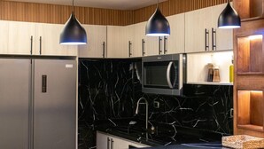 Eine moderne Küche mit schwarzem Marmorfliesenspiegel, Edelstahlgeräten und Holzschränken.