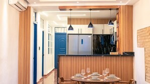 Eine moderne Küche mit Einbaukühlschrank, Holzvertäfelung und Pendelleuchten.