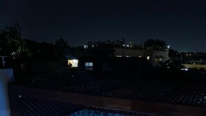 Ein Whirlpool mit Steinfassung, einer Holzterrasse und Blick auf die nächtliche Umgebung.