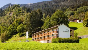 A hotel with multiple balconies, surrounded by lush greenery and mountains. - Hapimag Resort Andeer (Andeer)