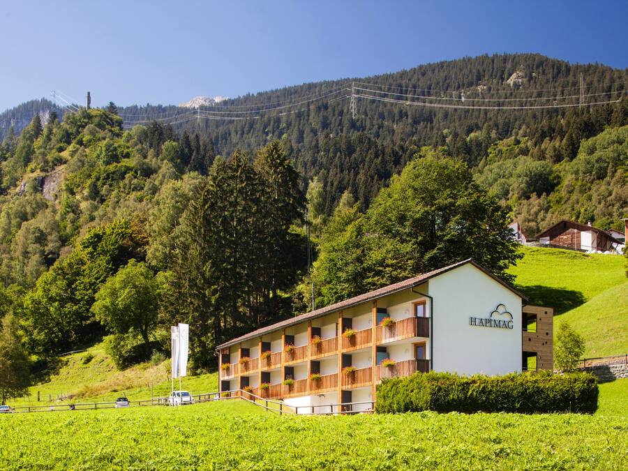 Un hotel con varios balcones, rodeado de exuberante vegetación y montañas.