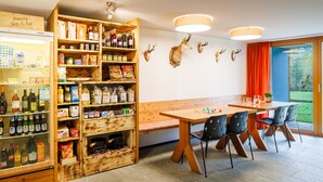 A restaurant with wooden shelves stocked with food and beverages, a wooden bench, and a table with chairs. - Hapimag Resort Andeer (Andeer)