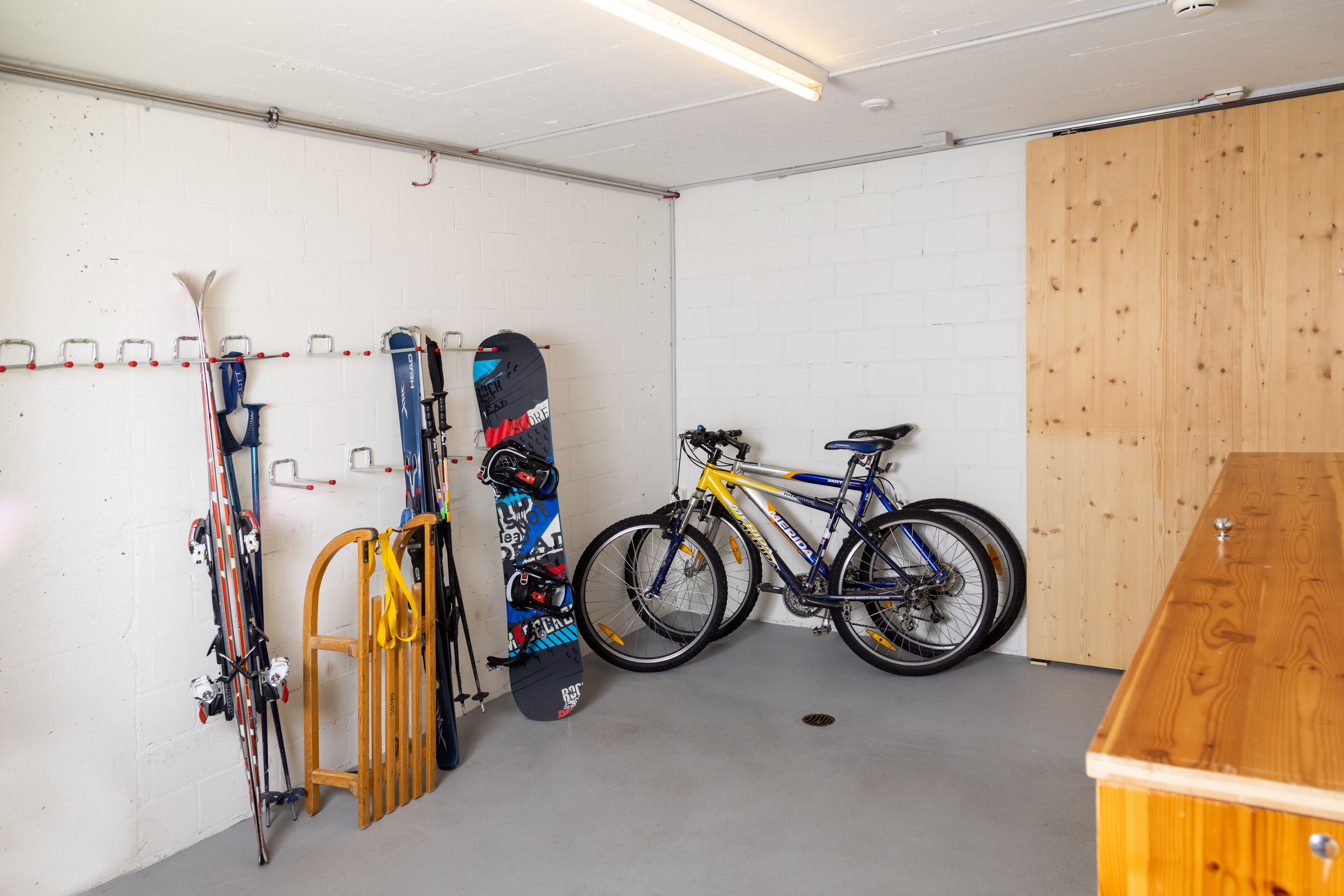A garage with skis, a snowboard, and a bicycle.