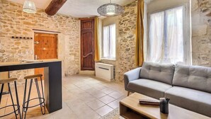 A cozy living area with a stone wall, a wooden door, a sofa, and a bar with stools.