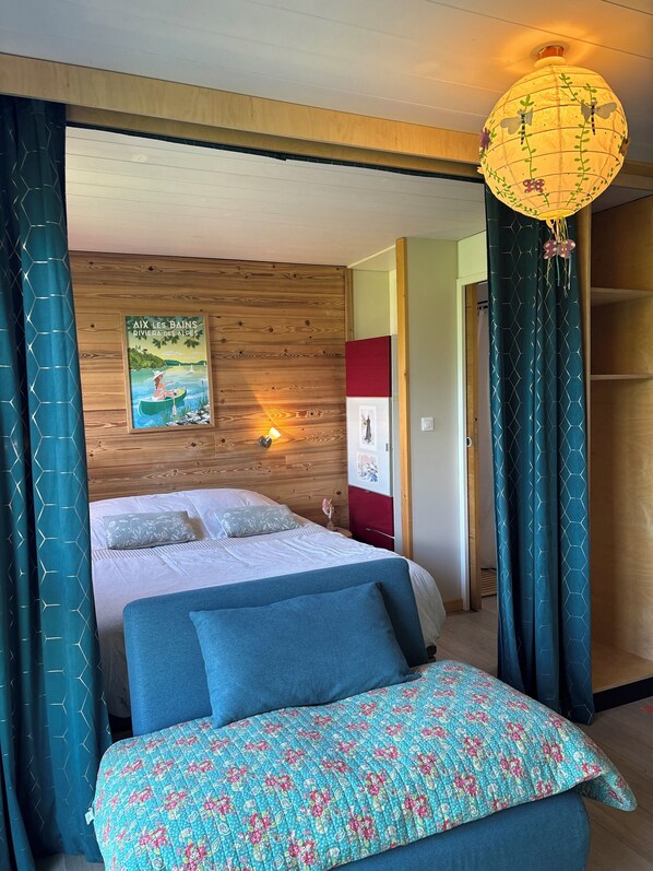 Un dormitorio con cabecera de madera, cama con edredón floral, lámpara de pared y un cartel.