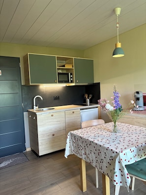 Una cocina compacta con microondas, pileta y armarios de madera.