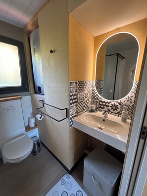 Ein kleines Badezimmer mit Toilette, Waschbecken und Spiegel.