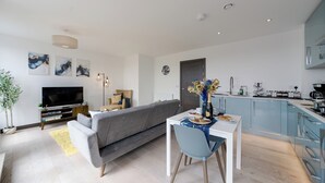 Ein modernes Wohnzimmer mit grauem Sofa, einem Flachbildfernseher und Kunstwerken an der Wand.
