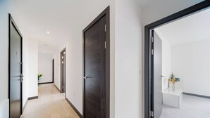 Ein moderner Flur mit dunklen Holztüren, einem hellen Boden und einer weißen Wand.