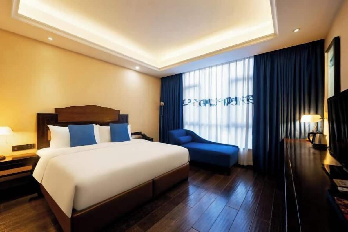 A hotel room with a large bed, a seating area, and a TV.