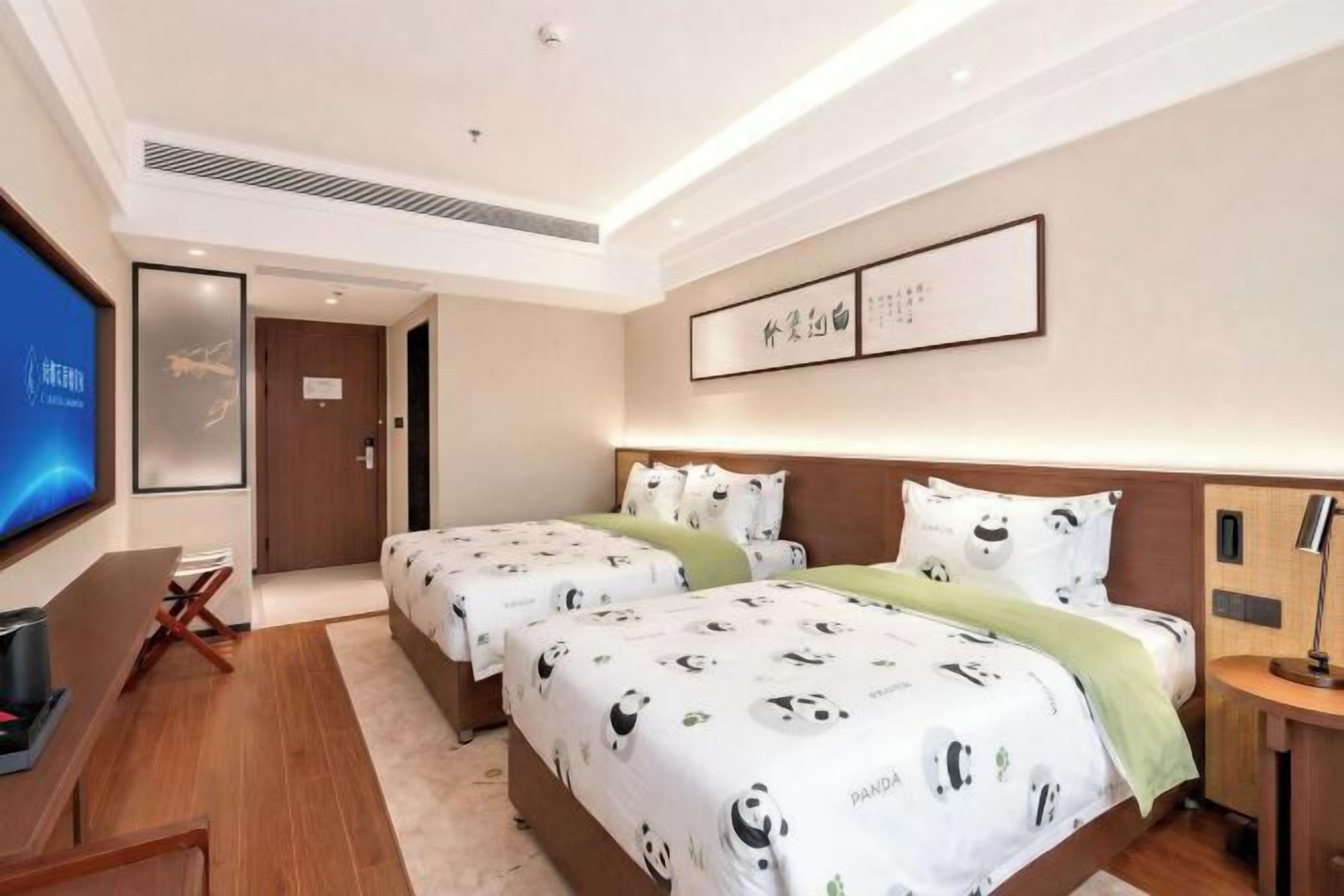 Une chambre d’hôtel avec deux lits, une télévision, un bureau et une porte donnant sur une autre chambre.
