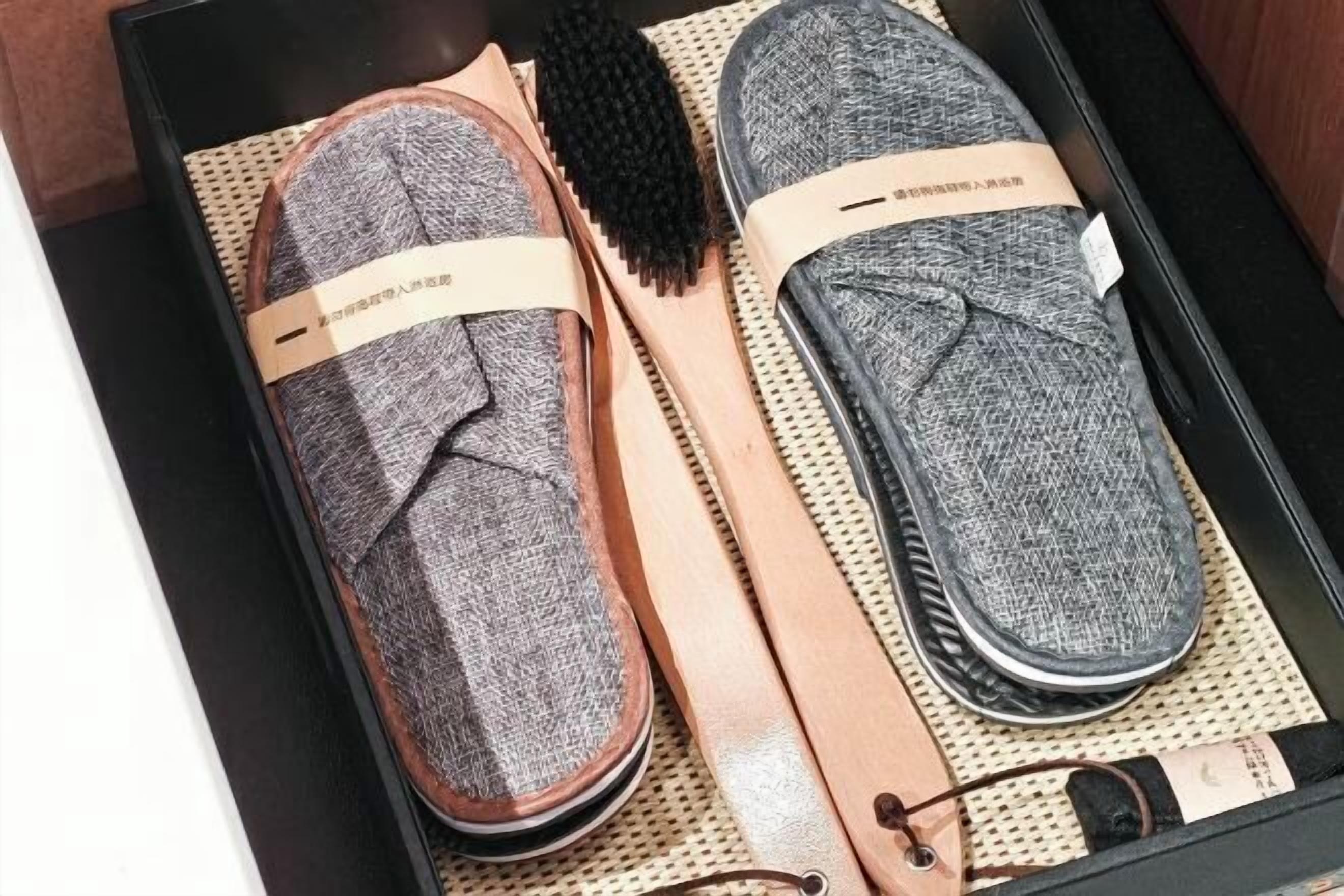A pair of slippers and a brush in a box.