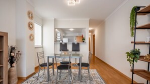 A modern dining area with a glass table, four chairs, and a patterned rug. - Sunflower Stay by Homie (Santa Cruz)