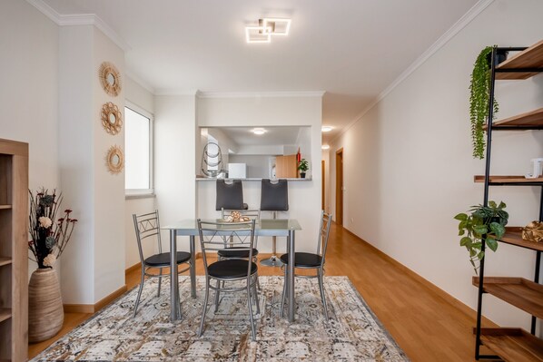 Uma zona de refeições moderna com mesa de vidro, quatro cadeiras e um tapete estampado.