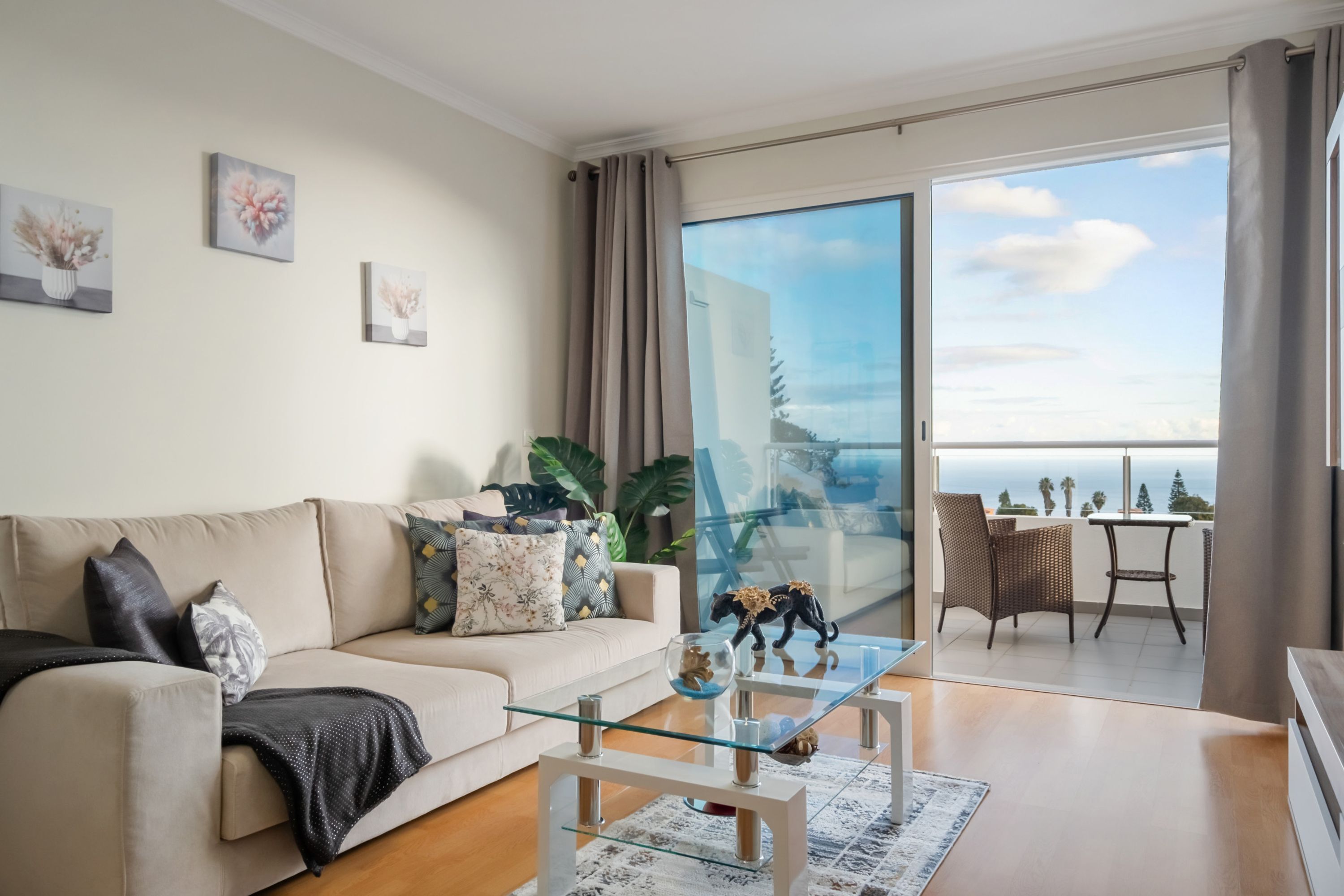 A modern living room with a sofa, coffee table, and a balcony with a view.
