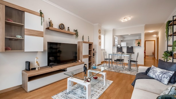A modern living room with a flat-screen TV, a glass coffee table, and a sofa. There is a dining area with a table and chairs. - Sunflower Stay by Homie (Santa Cruz)