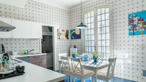 A modern kitchen with white cabinetry, a dining area with white chairs, and a large window with a view.